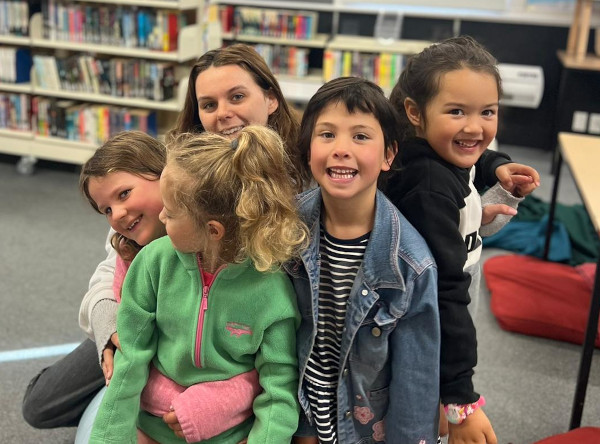 Pride Lands mentor and a group of young cubs on a childcare visit to a library.