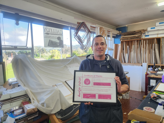 Simon from The Lewis-Paape Gallery with their Help 100 Sponsor certificate.