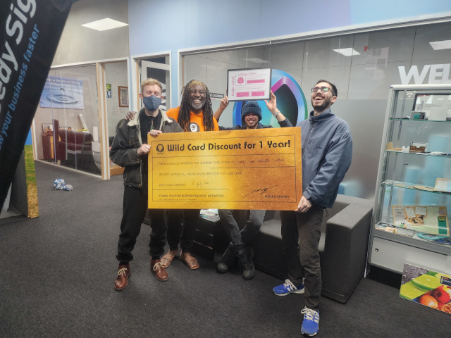 Moses presents a certificate to Help 100 Sponsors Speedy Signs